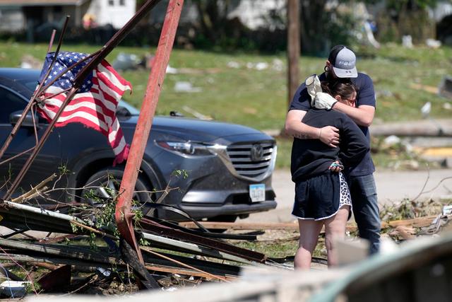 Residents hug in front of their tornado damaged home in Greenfield, Iowa