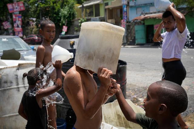 A child covers his head with a bucket on a hot day in the Los Guandules neighborhood 