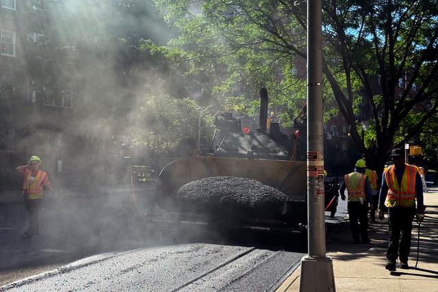 A road crew repaves a road in the Forest Hills neighborhood in the Queens borough of New York