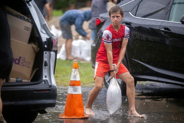 Brantley Schnabel helps his family carry sandbags to their van while preparing for Hurricane Debby at a county park in Savannah, Ga.